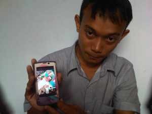 Rudiato, ayah kandung balita malang saat menunjukan foto anaknya lewat ponsel, foto Hermanto