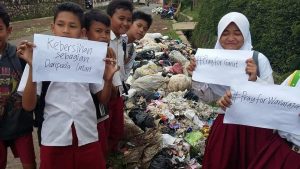 Anak-anak SD ini tampak protes dengan poster kertas putih bertuliskan sindirian atas menumpuknya sampah dipinggiran jalan, foto Istimewa